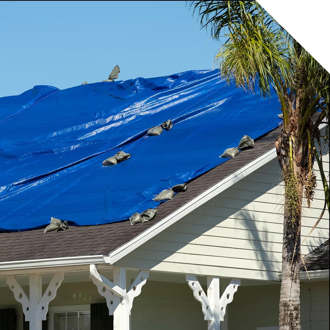 House with blue tarp on roof after hurricane damage