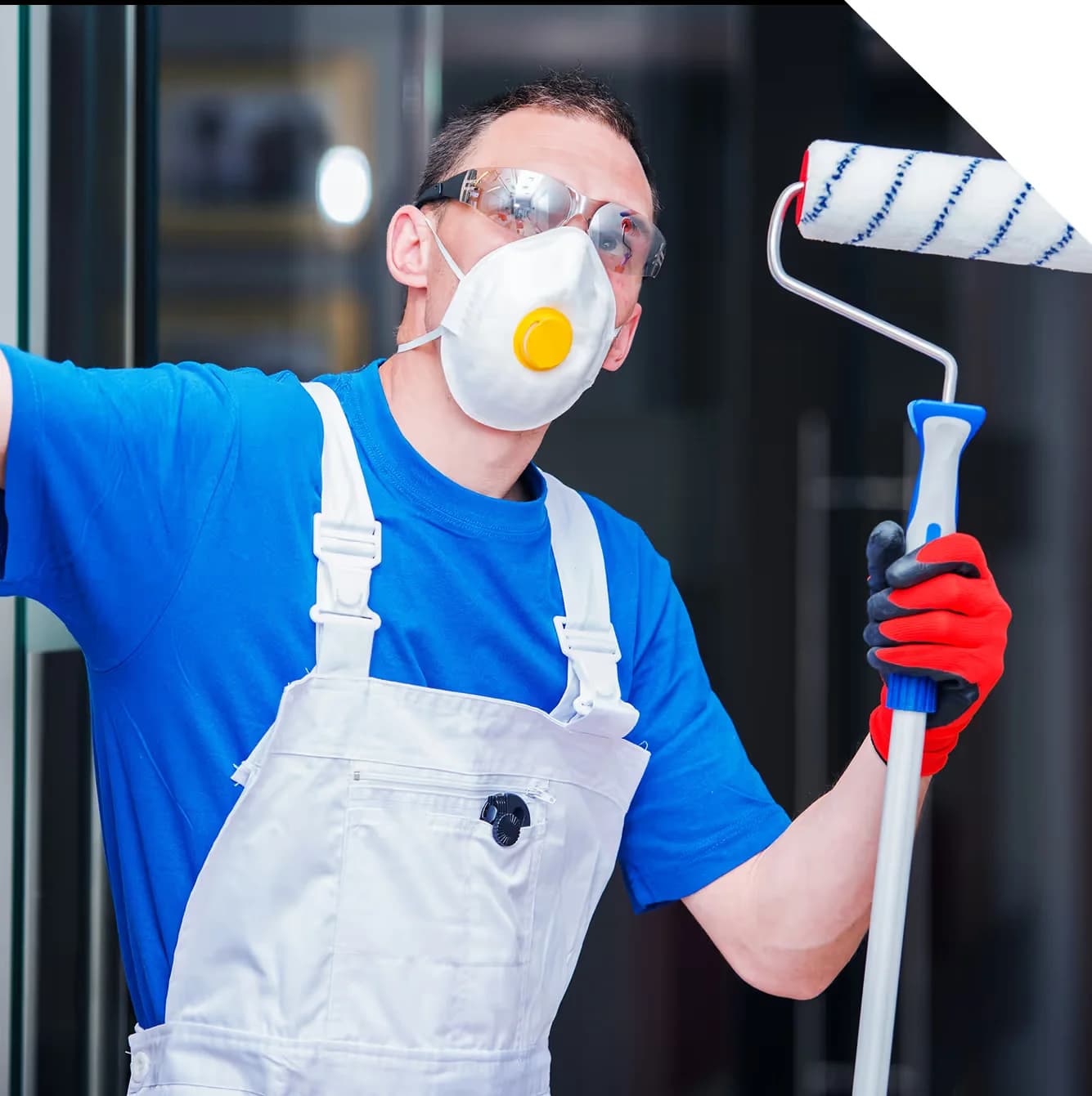painter wearing facemask holding a long handle paint roller