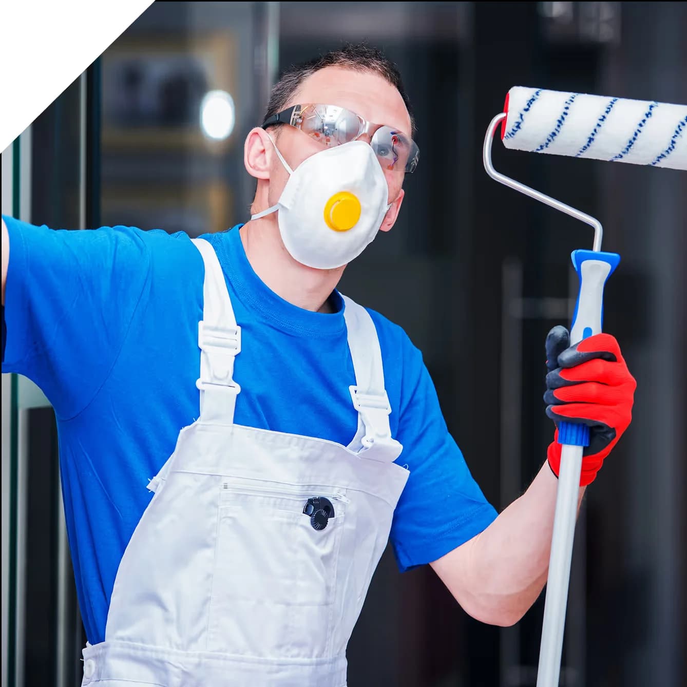 painter with facemask holding a long paint roller